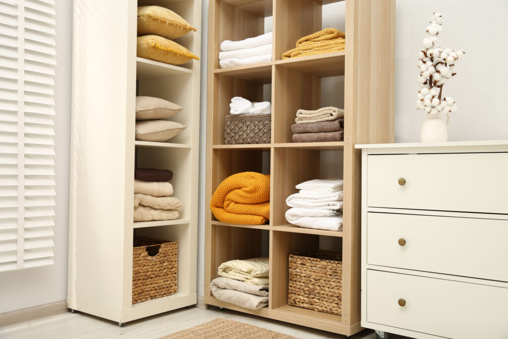 Home textile organization. Folded towels, blankets and pillows on shelving units indoors
